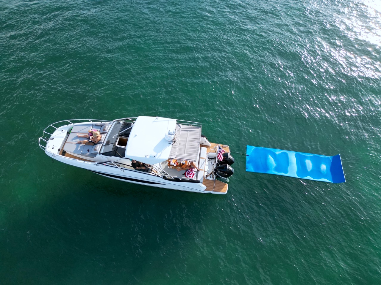 Overhead view of the Beneteau Flyer 32 charter boat with floating mat and guests swimming